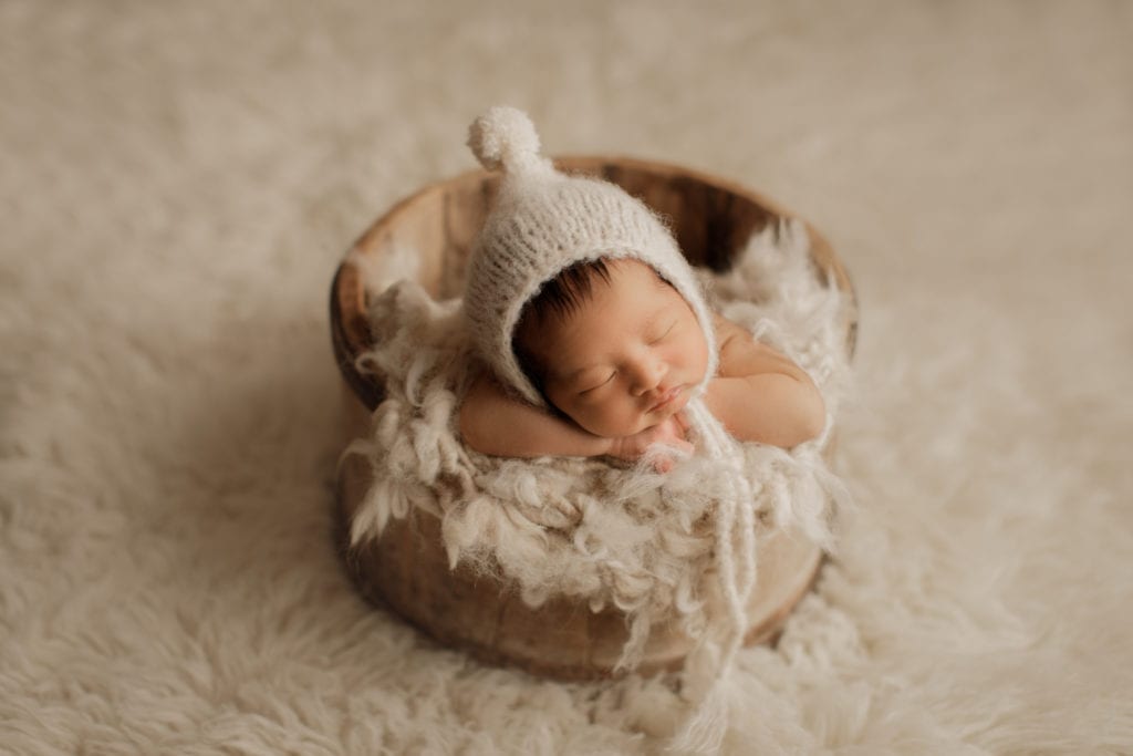 newborn boy in bowl with cozy hat 