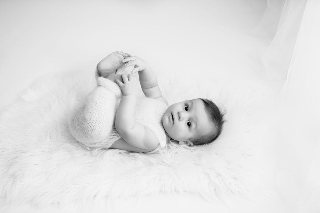 black and white image of baby playing with his feet