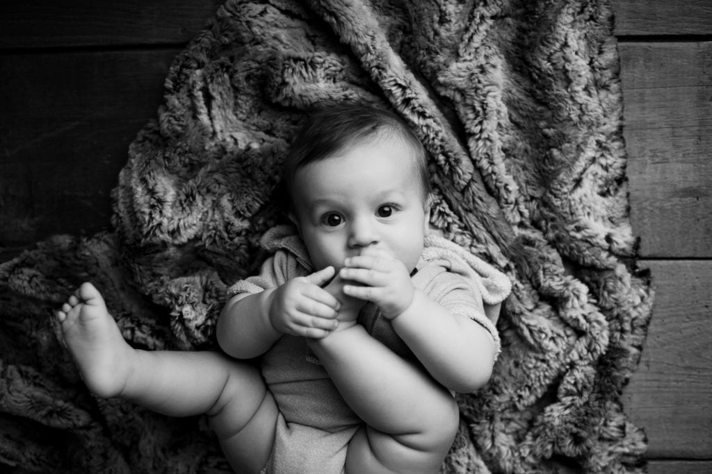 black and white photo 6 month old eating toes