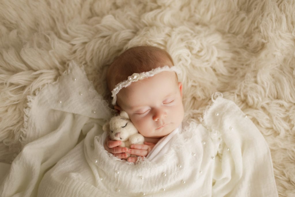 sleeping newborn girl and a stuffed animal