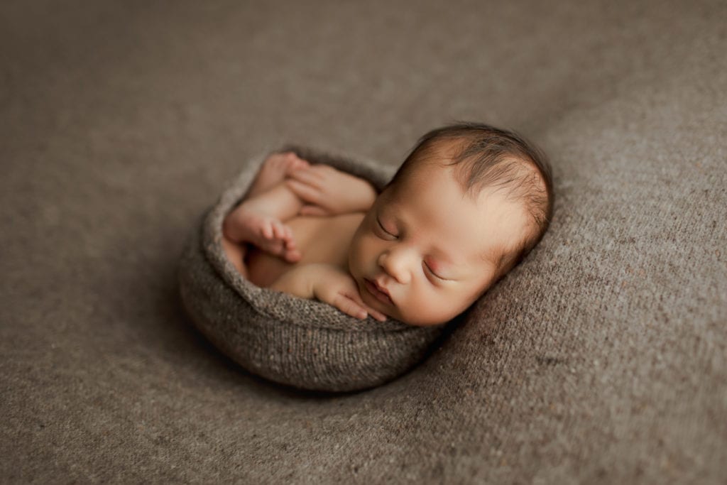 baby boy swaddled in newborn photo shoot