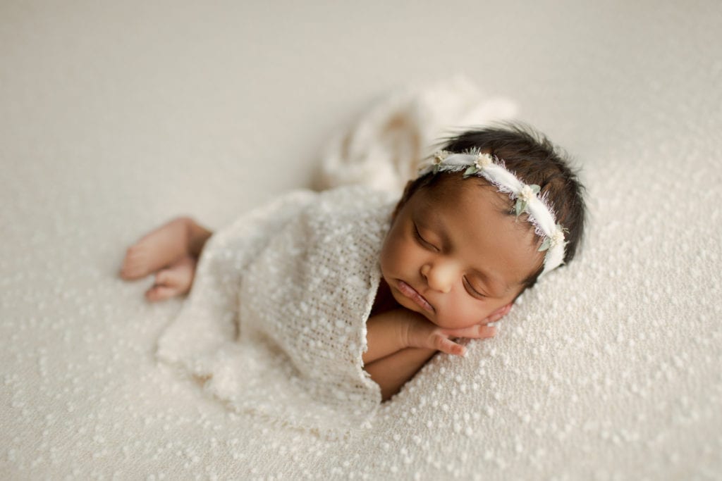 newborn baby snuggling in white