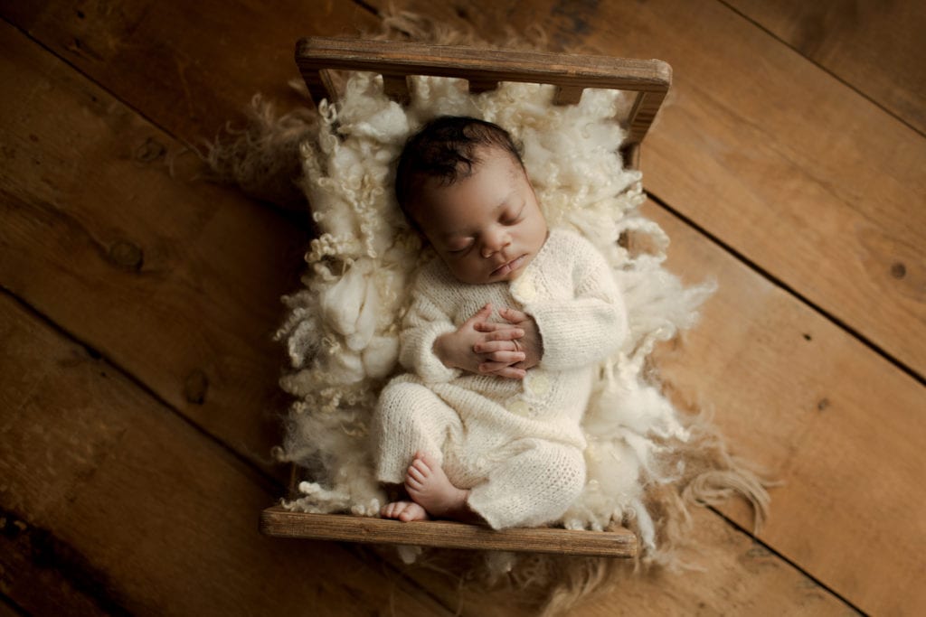 newborn baby in wooden doll crib