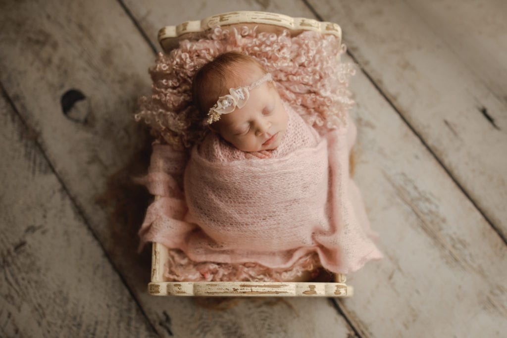 newborn baby girl in mini crib