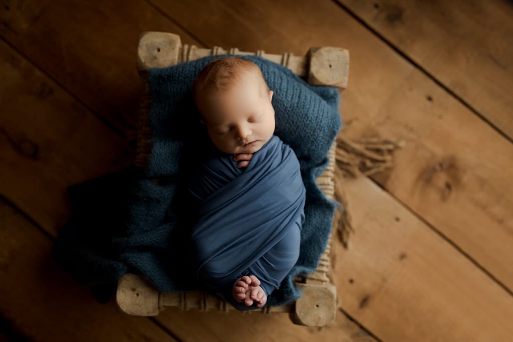 best chicagoland newborn photographers, swaddled baby in blue asleep on bed