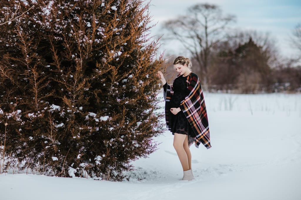 mother-to-be standing on snowy landscape