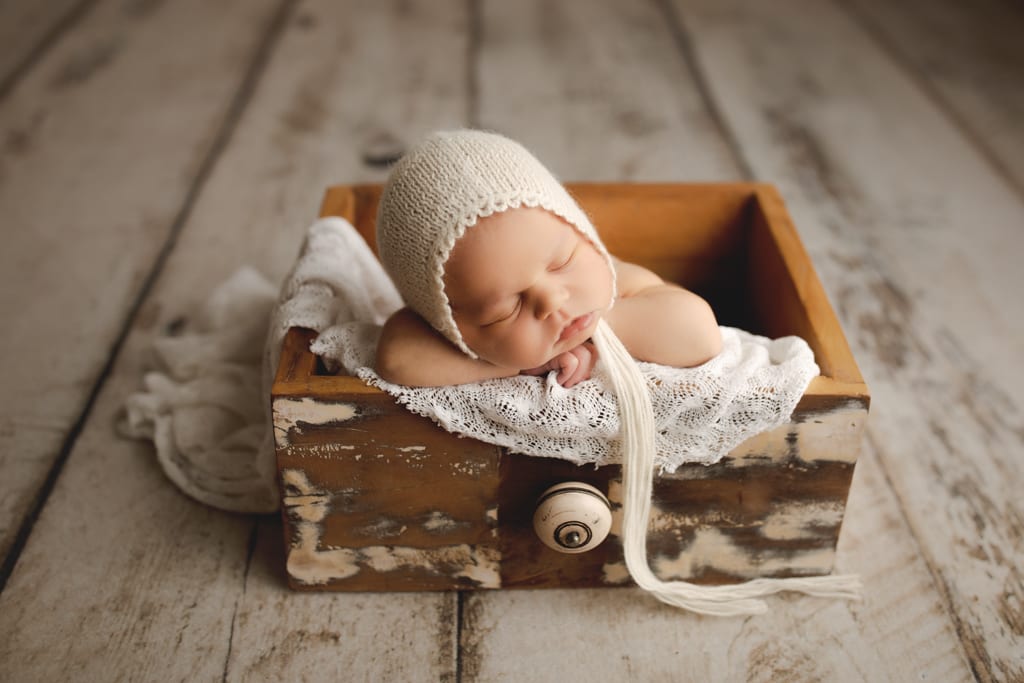 infant asleep in distressed wood drawer