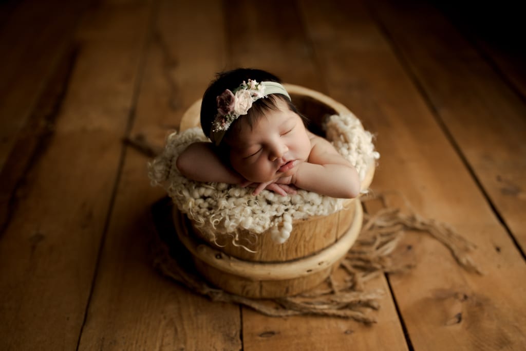 newborn photographer near me, baby girl asleep in wooden bucket