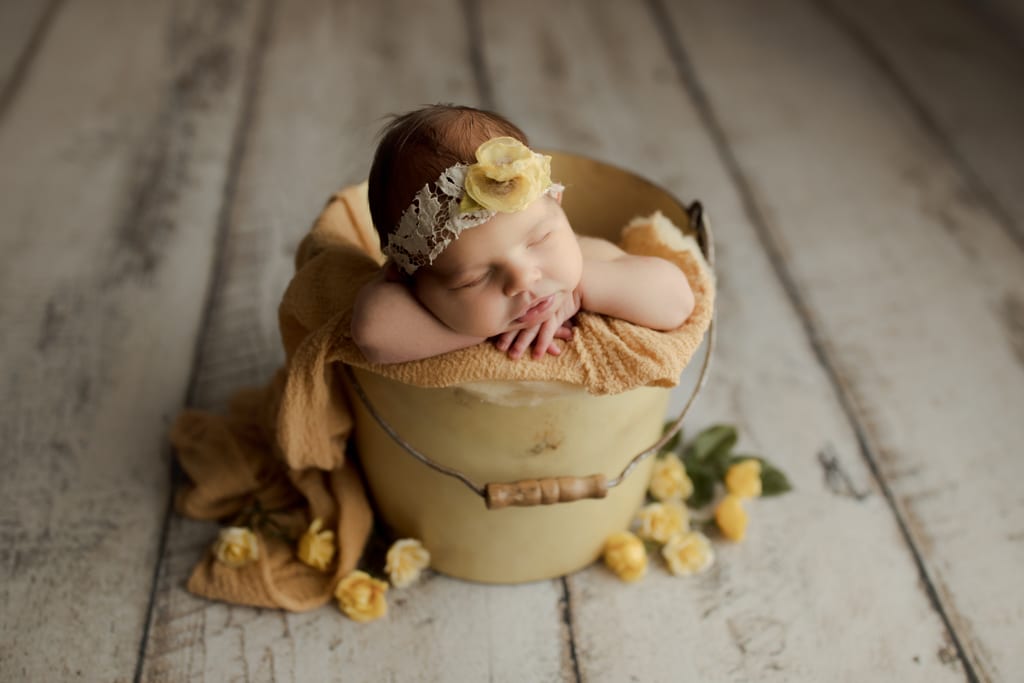 Best Chicago newborn photographers, baby girl asleep in bucket with yellow flowers