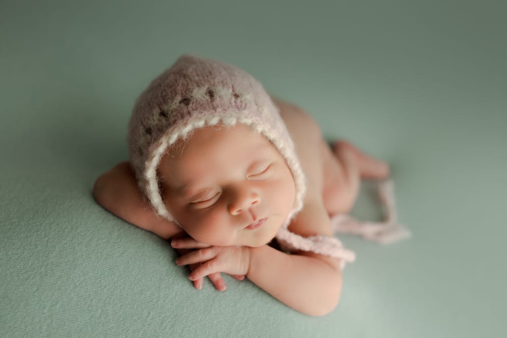 best newborn photographers near me Arlington Heights, baby girl in knitted cap asleep on beanbag