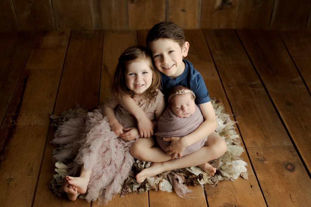 Chicago baby and sibling photos, newborn girl being held by big brother and sister