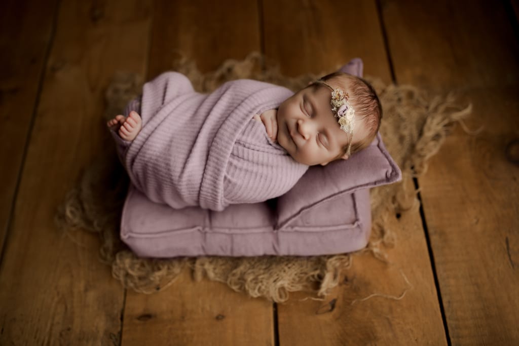 newborn photography near me Chicago, baby girl asleep on purple cushions
