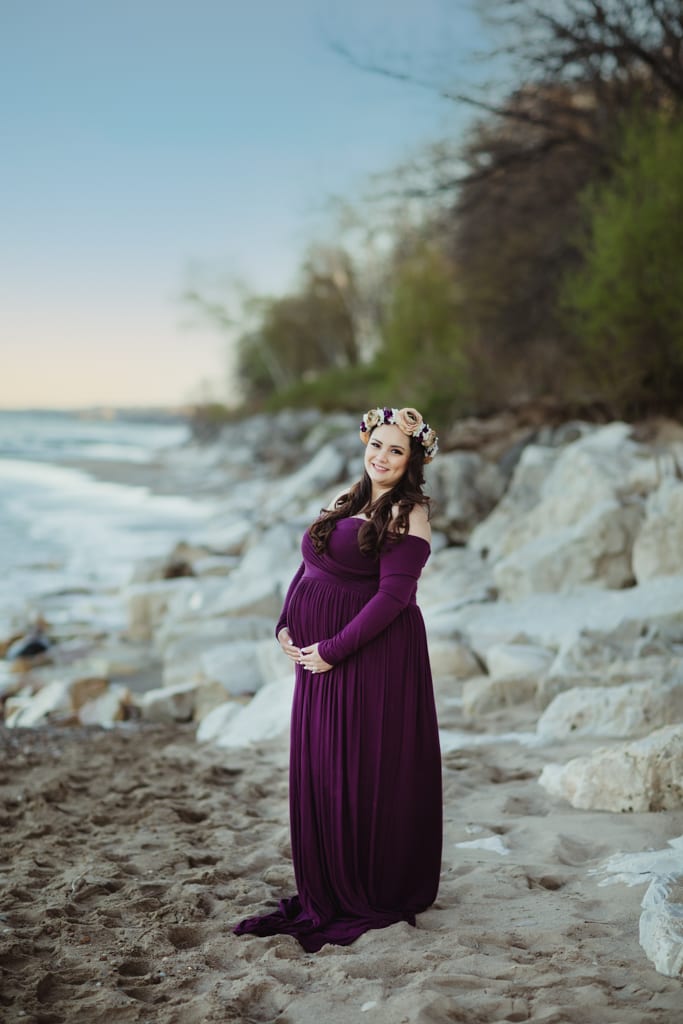 outdoor maternity photographers near me Chicago, woman in purple maternity gown and flower crown on beach at sunset