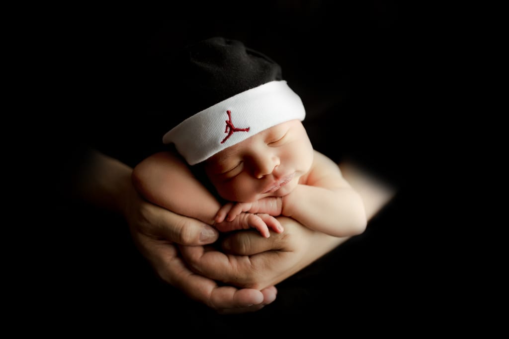 baby boy wearing sports sweatband asleep in dad's hands