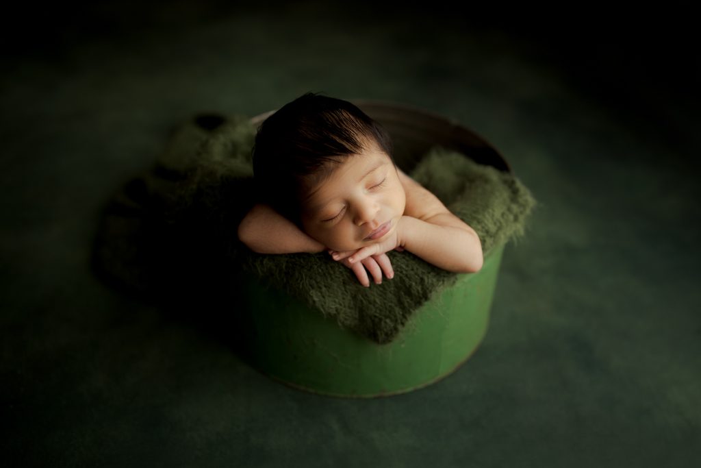 Infant boy asleep in green bucket, Chicago newborn photographer