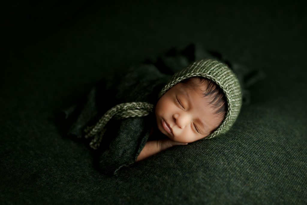 Palatine newborn pictures, baby boy in yarn cap asleep on dark green beanbag