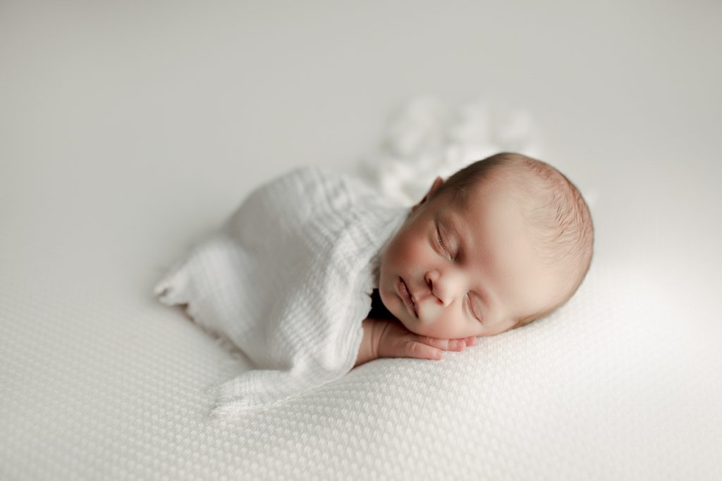 Chicago newborn photographer, infant asleep on white beanbag with white blanket