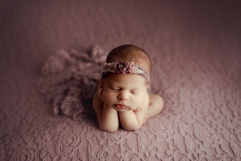 Sleepy newborn girl in purple blanket and headband