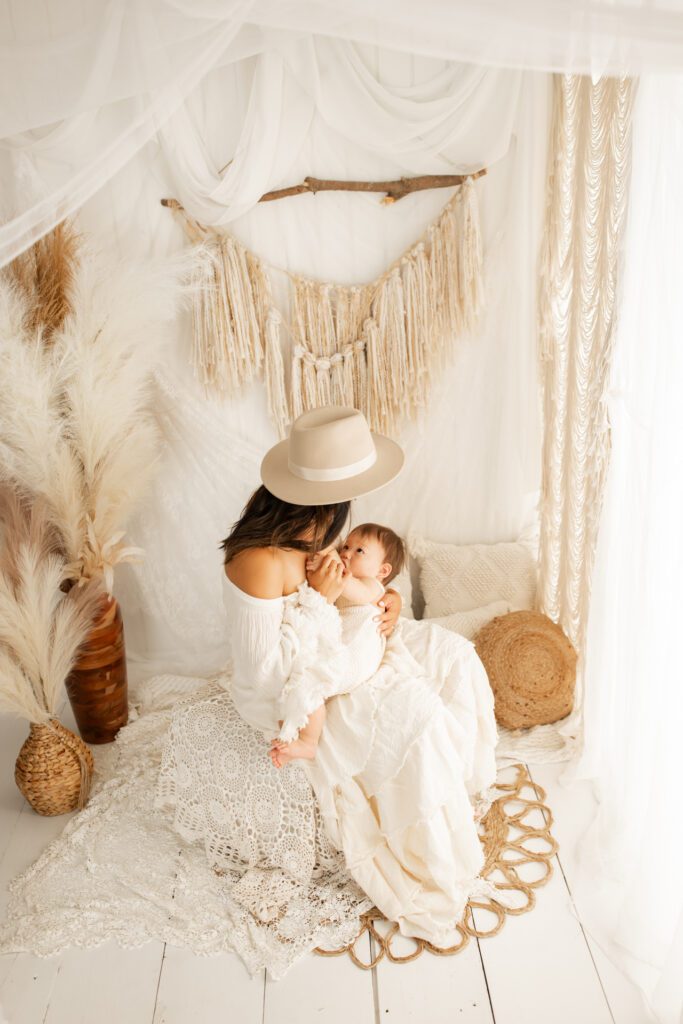 Mom in flowy dress and cowboy hat breastfeeding baby