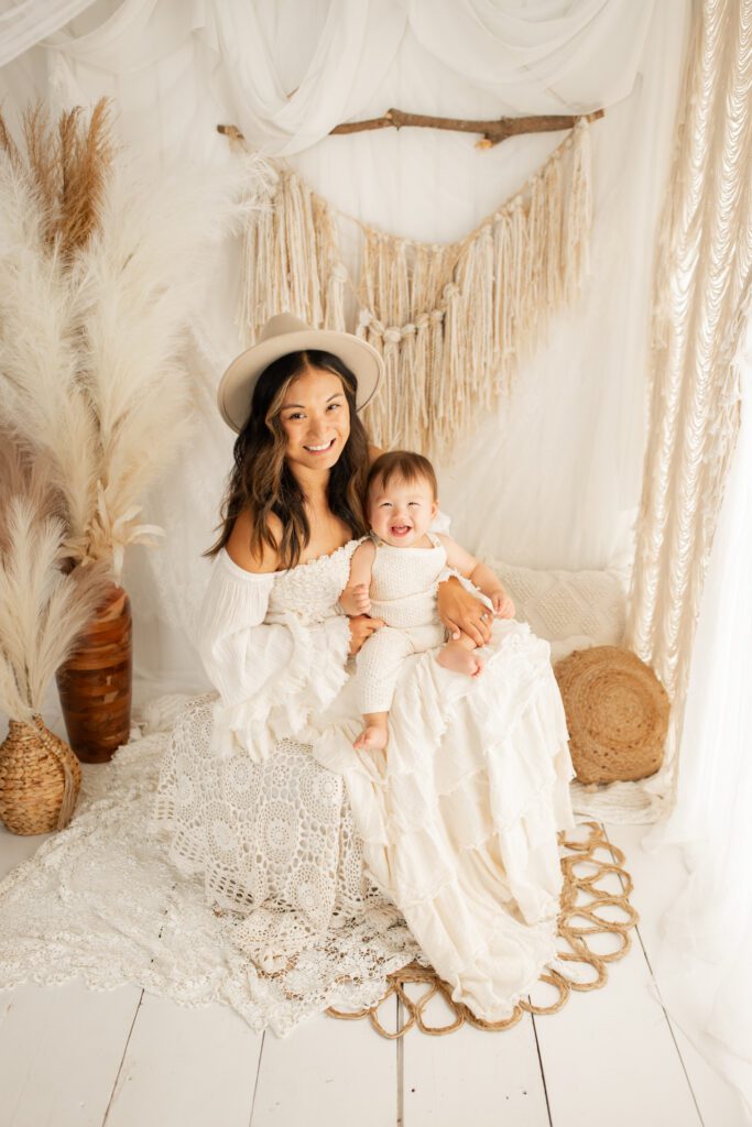 Mom and baby seated in photography studio with boho backdrop