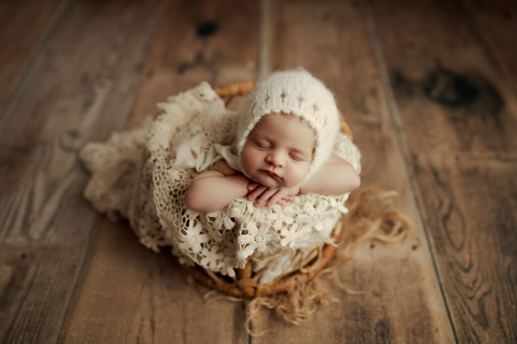 Baby girl asleep in woven basket with floral lace wrap