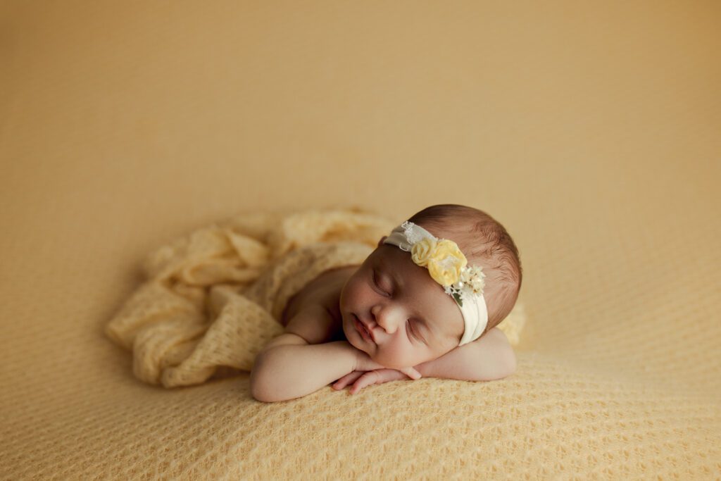Baby girl in yellow wrap asleep on textured bean bag