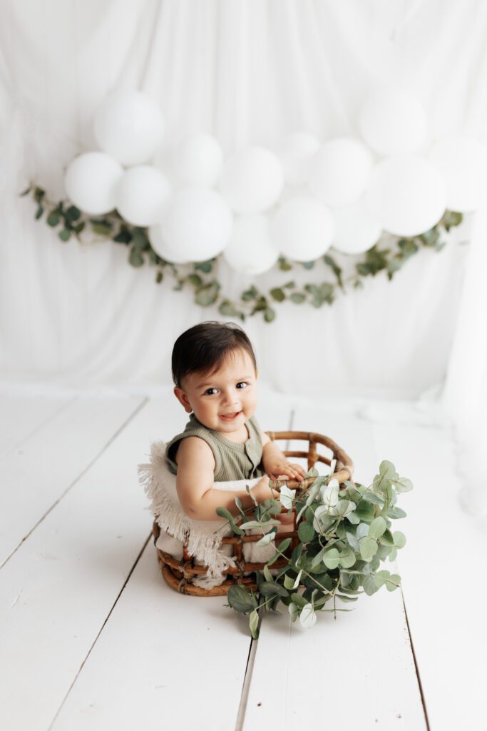 Baby in basket holding greenery