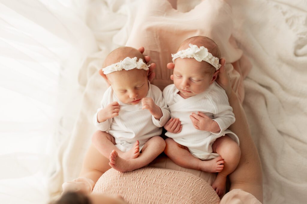 Mom holding newborn twin girls on her lap in Chicago area studio