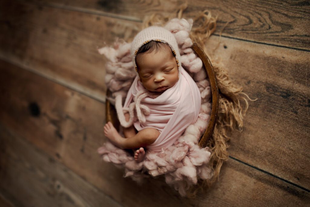 Newborn girl in pink swaddle in photo studio near Chicago