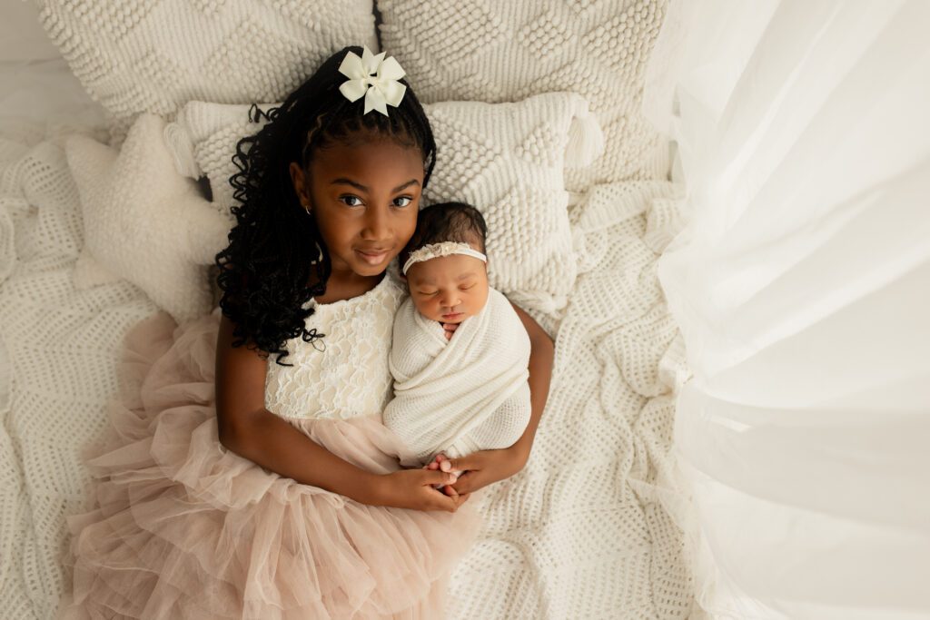 Little girl holding newborn sister at Chicago photo studio