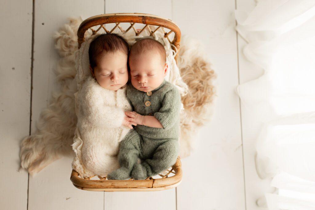 Newborn twin boys dressed in soft colors