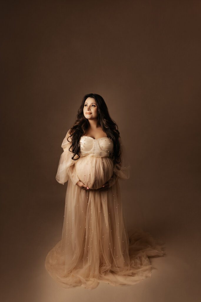 Woman in beaded blush maternity gown in Chicago studio