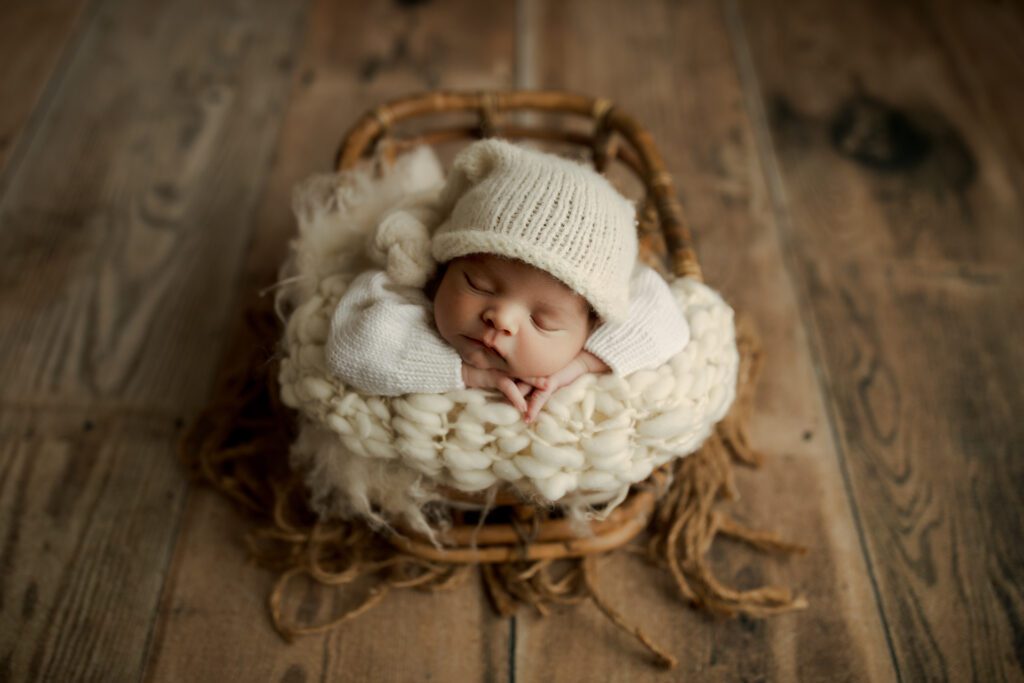 Baby in knitted cap asleep in basket in studio near Chicago