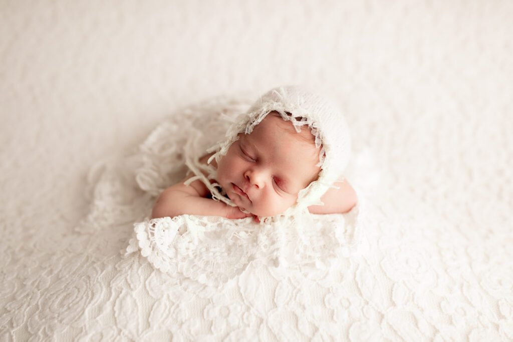 Baby girl in bonnet and lacy dress asleep in Long Grove Illinois photo studio