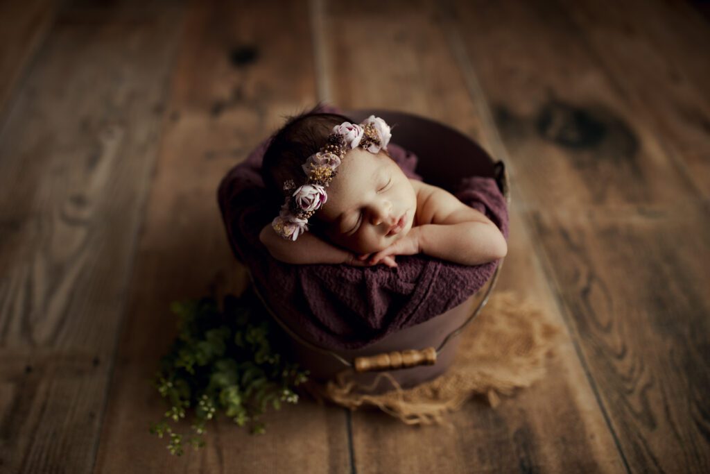 Baby girl asleep in bucket and wearing flower crown