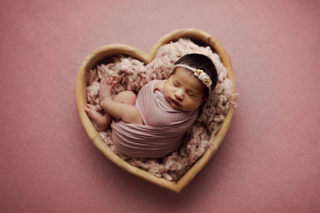Newborn infant lying in heart prop