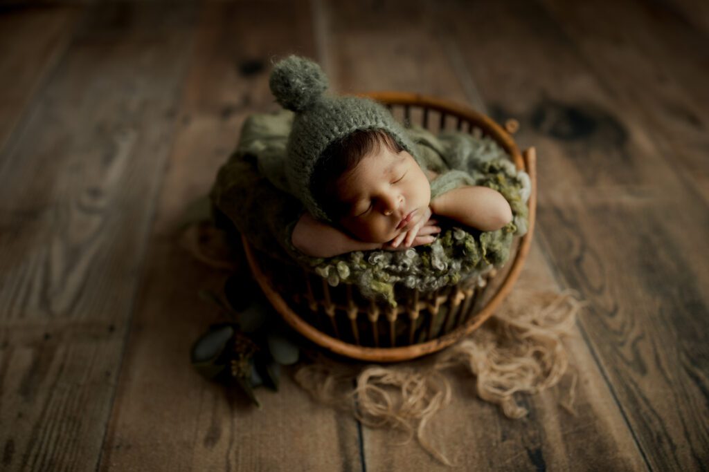 Baby boy in beanie cap asleep in bucket at Long Grove Illinois newborn studio