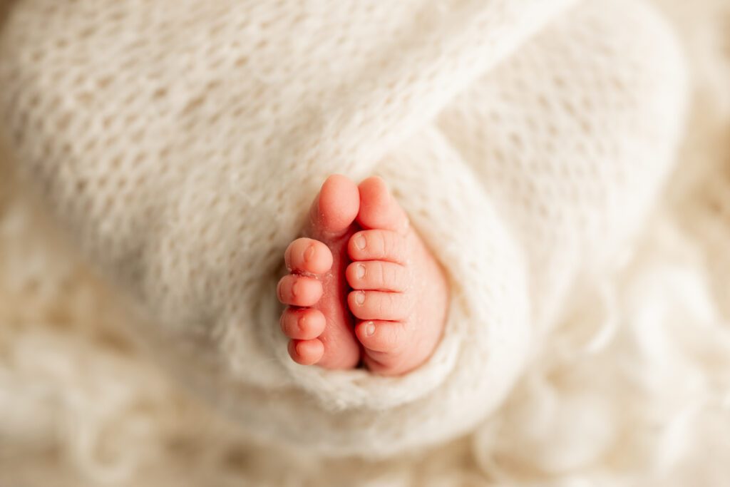 Closeup of baby toes in soft white swaddle