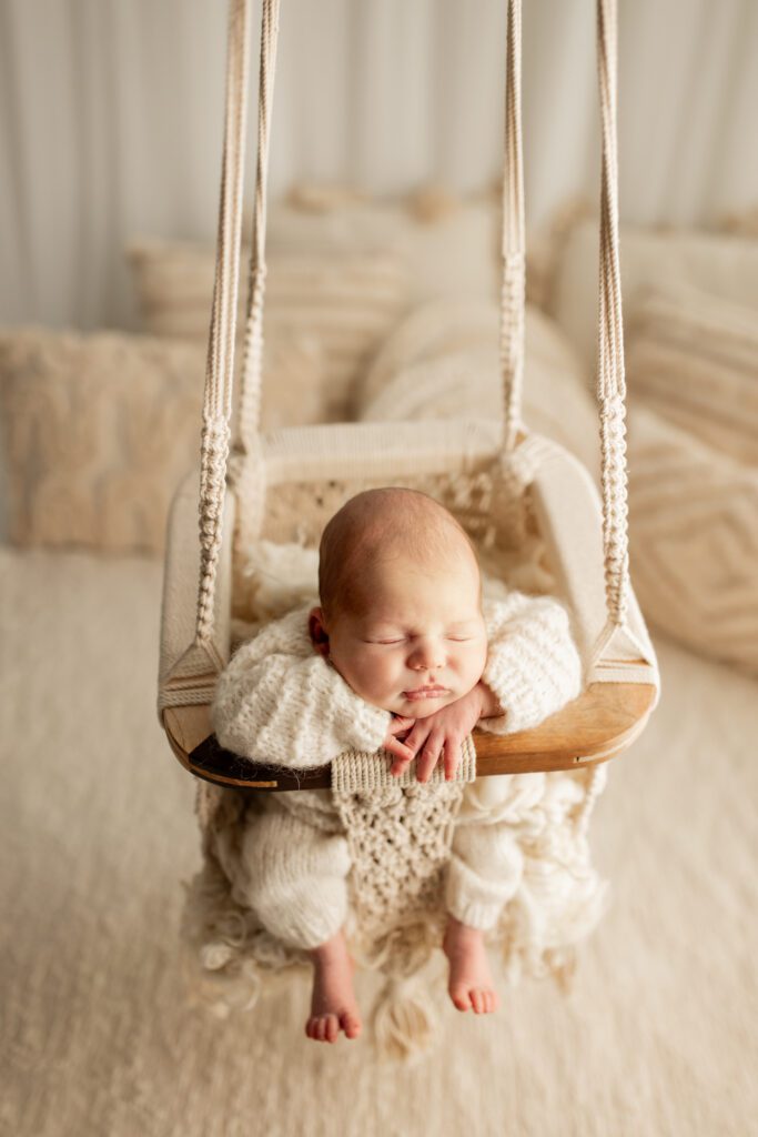 Newborn boy asleep in swing in studio of Chicago baby photographer Agata Brannon