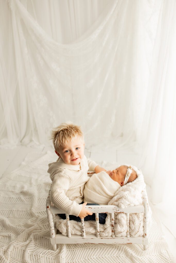 Toddler boy in crib with newborn sister in Chicago area photo studio