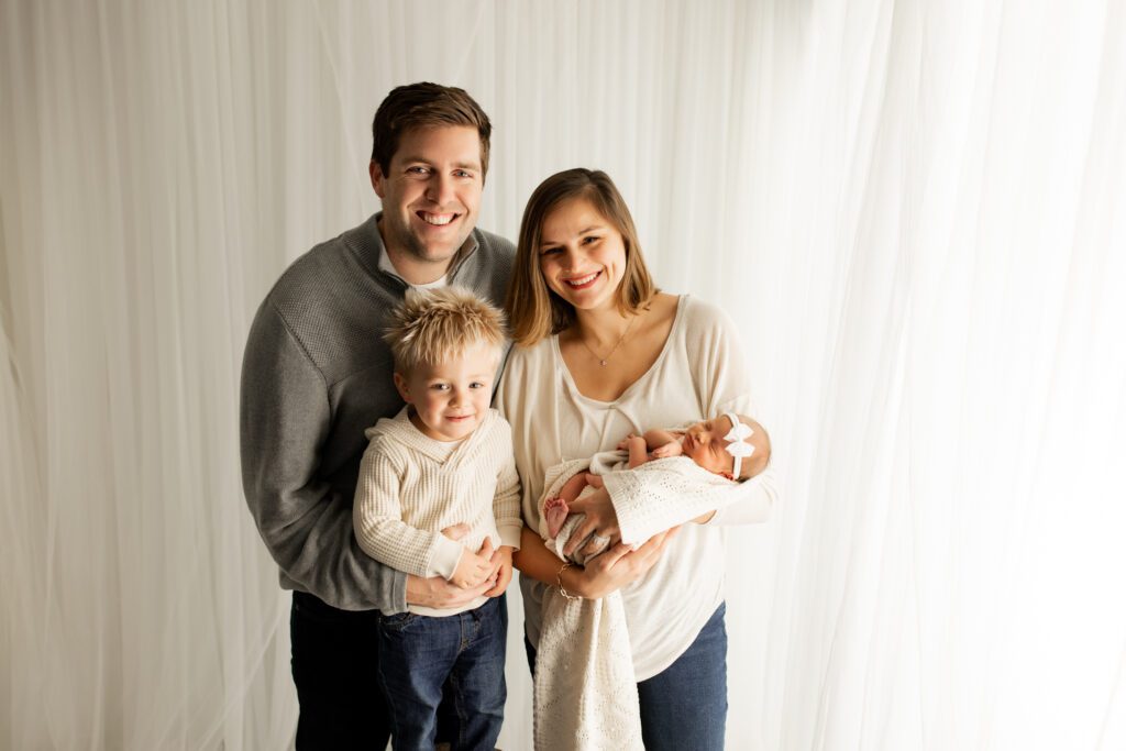 Lake Forest family with newborn standing near window