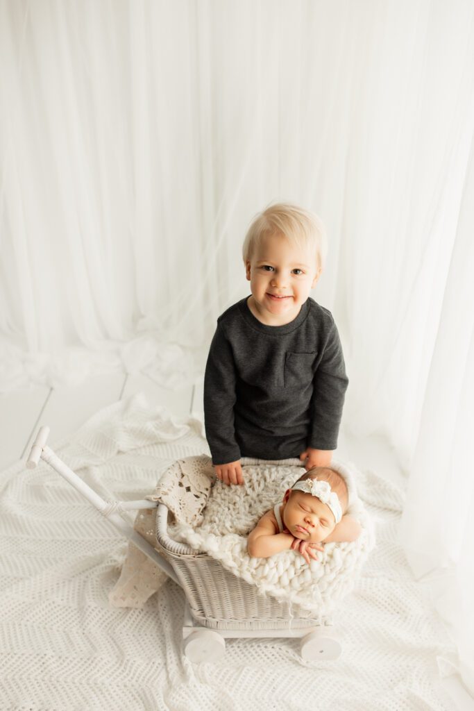 Big brother standing next to new baby sister in photo studio near Lake Barrington