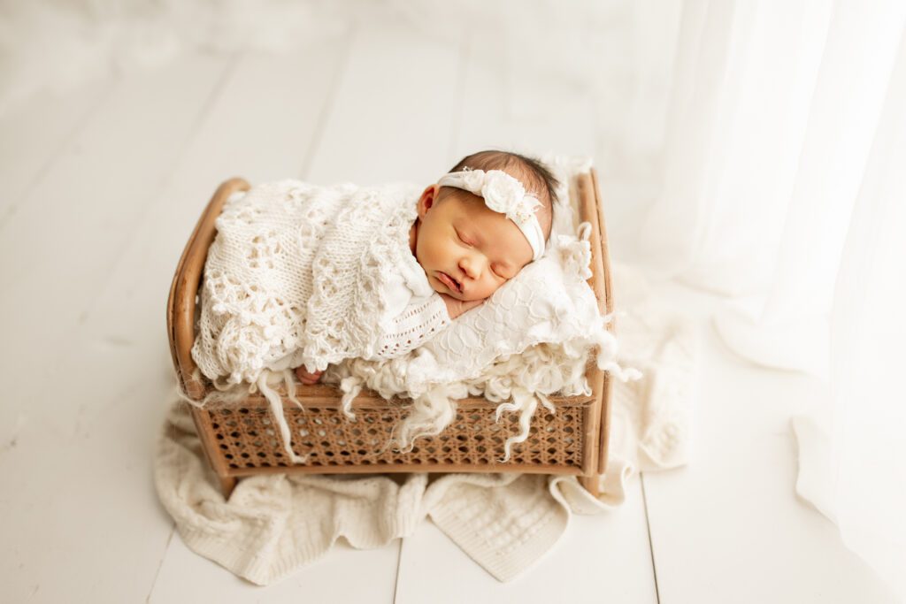 Baby girl asleep in tiny wicker crib in Long Grove IL studio