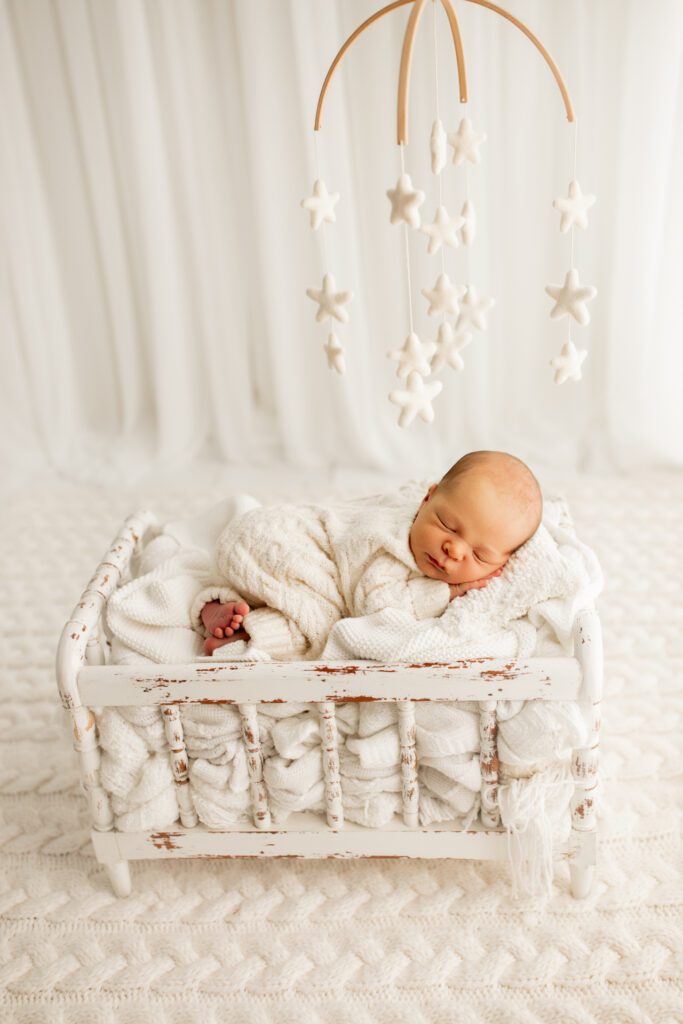 Infant asleep in crib with star mobile hanging above him