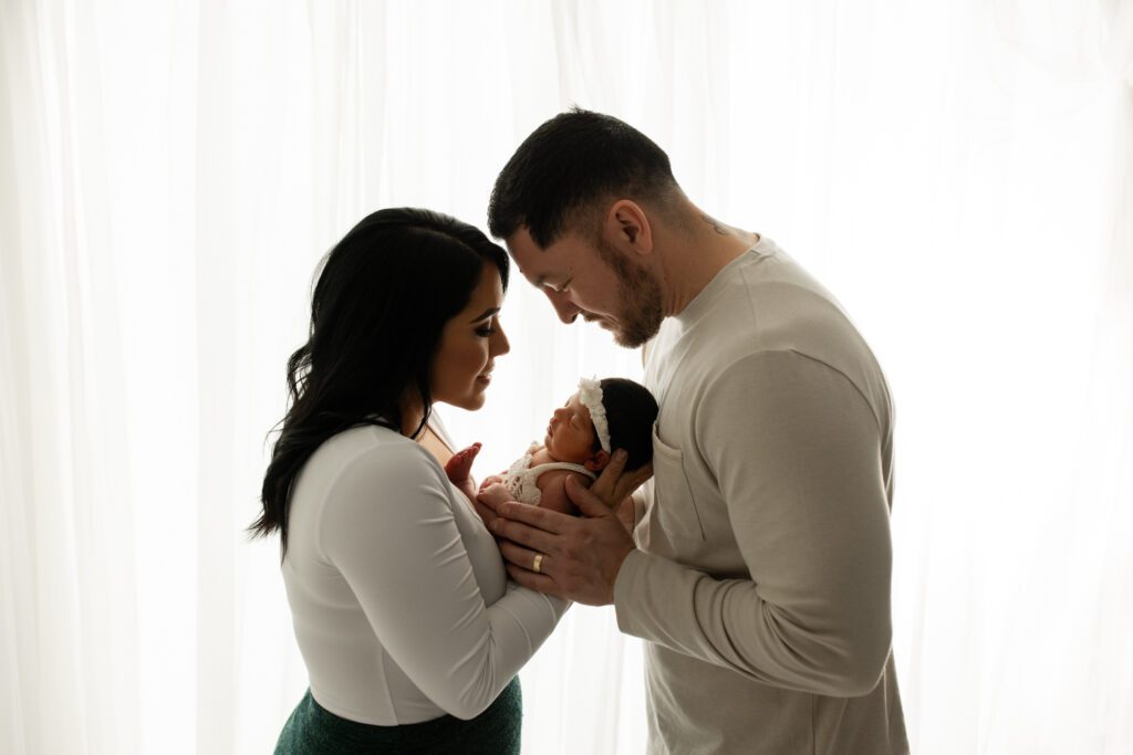 Parents holding new baby daughter in newborn photo studio Chicagoland