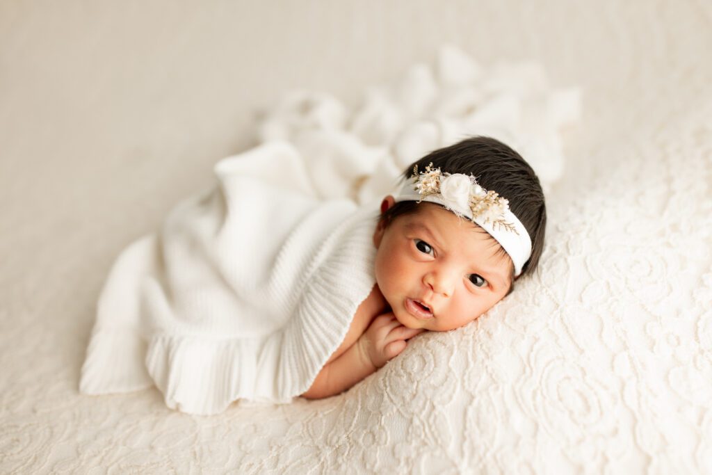 Wakeful baby girl with white blanket and headband