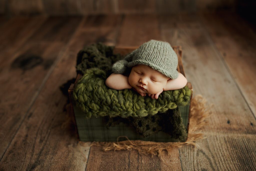 Baby boy in gray cap asleep in box in studio near Park Ridge Illinois