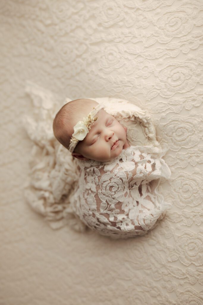 Baby girl asleep in creamy lace wrap and headband in Chicagoland studio