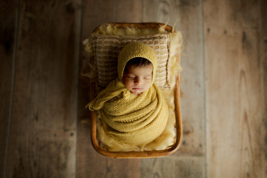 Sleeping new baby wrapped in soft yellow fabric