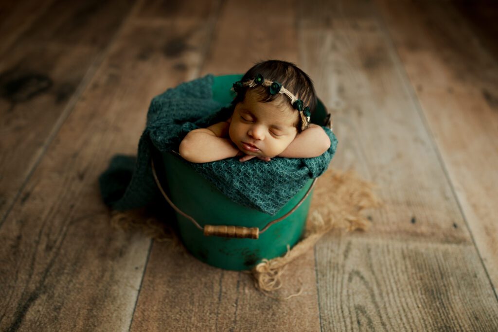 Infant in green swaddle and bucket in Long Grove Illinois photo studio